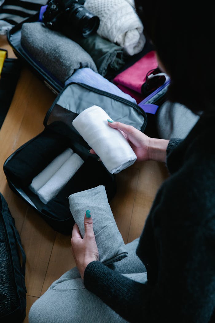 Person packing and organizing clothes in a suitcase for travel.